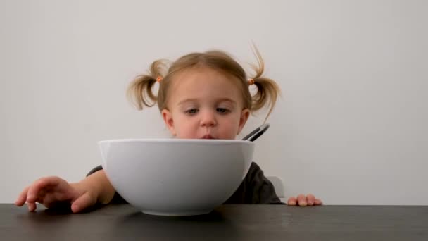 Linda niña pequeña buscando en un tazón de cerámica grande — Vídeos de Stock