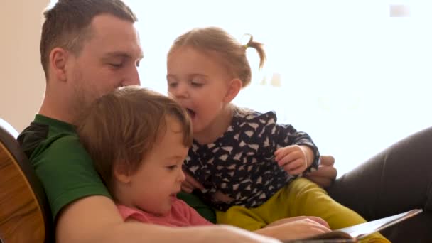 Père lisant le livre aux enfants sur le canapé — Video
