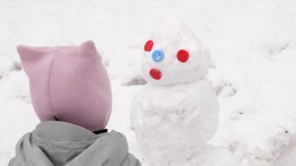 Baby kind met sneeuwpop in de winter straat — Stockvideo