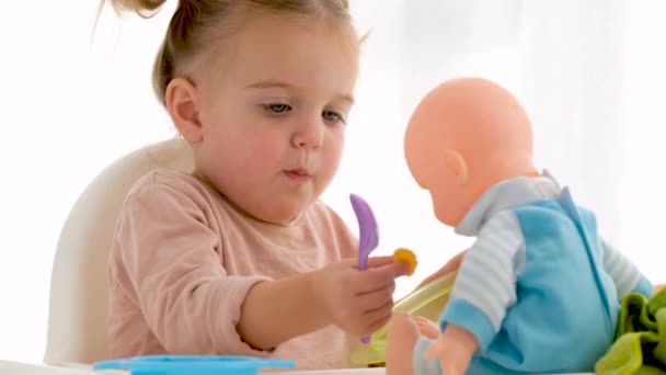 Маленькая девочка делится едой с куклой — стоковое видео