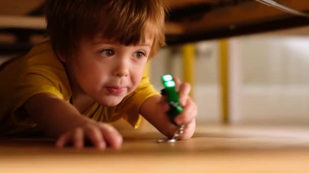 Niño pequeño con linterna escondida debajo de la cama — Vídeo de stock