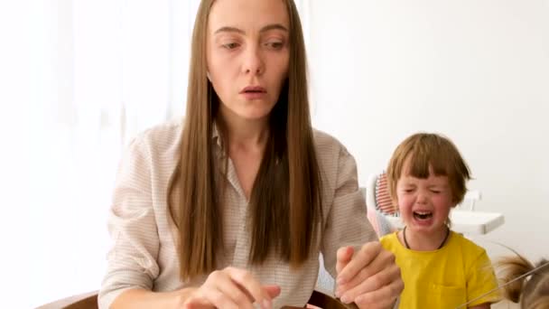 Втомлена жінка працює біля сина, що плаче — стокове відео