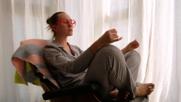 Pijamalı kadın sandalyede meditasyon yapıyor. — Stok video