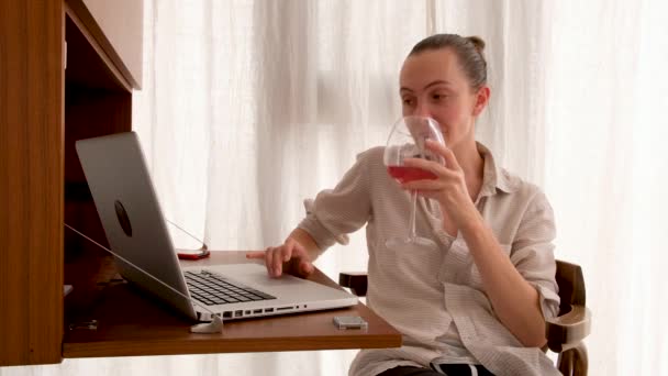 Mujer trabajando en un portátil con una copa de vino — Vídeo de stock