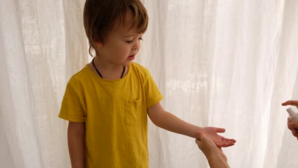 Родитель управляет детскими руками с помощью дезинфицирующего средства — стоковое видео