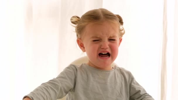 Девочка плачет в детском кресле, а мама успокаивается — стоковое видео