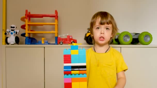 Rapaz bonito demonstra um brinquedo de torre feito de cubos — Vídeo de Stock