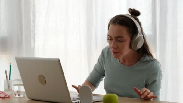 Mulher com fones de ouvido sentados na mesa — Vídeo de Stock