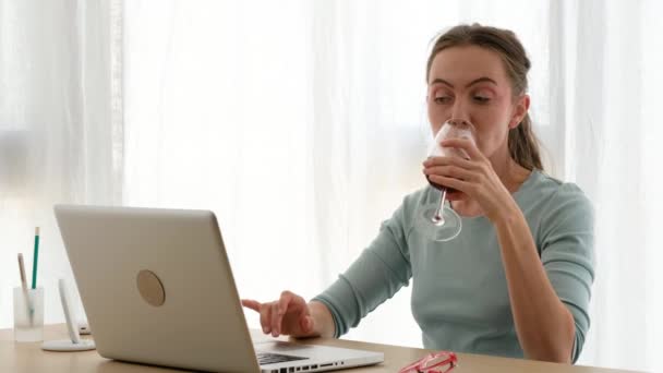 Mujer trabajando en un portátil con una copa de vino — Vídeo de stock