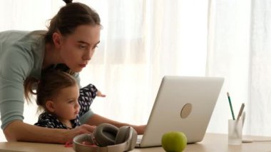 Anne ve küçük kızı evde dizüstü bilgisayar kullanıyorlar.