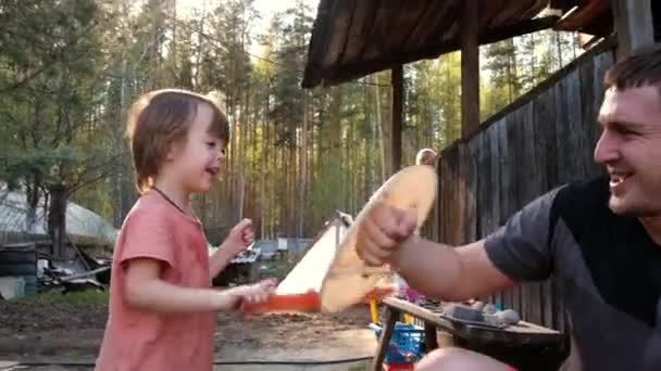 Szczęśliwy ojciec i syn dobrze się bawią na podwórku przed lasem iglastym w wiosce — Wideo stockowe