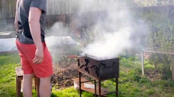 Hombre de las cosechas asar comida en brasero en el patio trasero — Vídeo de stock