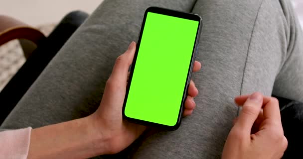 Vrouw bladert door een smartphone met een groen scherm — Stockvideo