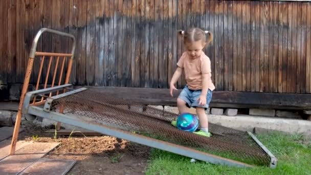 Lugn liten flicka spelar boll på gården på dagtid — Stockvideo