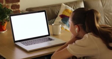 Kulaklıklı tanınmayan bir kadın boş ekranlı dizüstü bilgisayar izliyor.