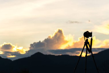 gündoğumu gökyüzü ile tripod üzerinde kamera silüeti 