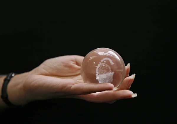 Bola de cristal en la mano sobre el fondo negro — Foto de Stock