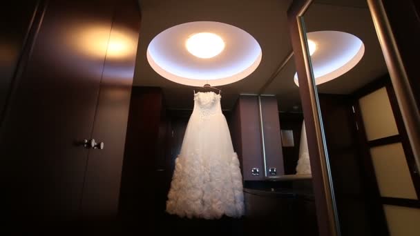 Vestido de novia blanco colgando en la habitación oscura — Vídeo de stock