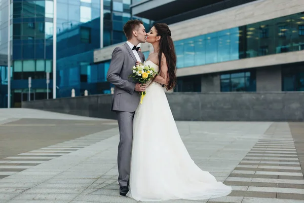 Newlyweds kissing in front of the building — Stock Photo, Image