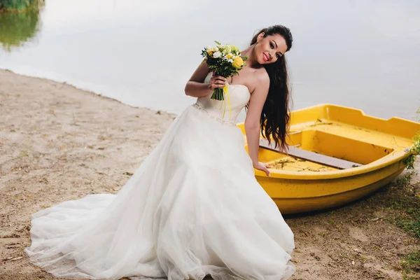 Nevěsta sedí na lodi na břehu řeky — Stock fotografie
