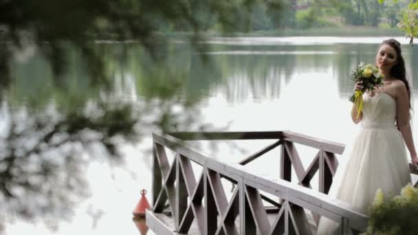 Bruden som står på piren i floden — Stockvideo