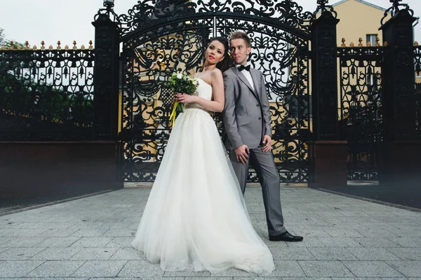 Newlyweds standing in front of the gates — Stock Photo, Image