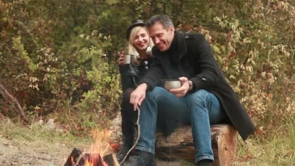 Ζευγάρι κοντά σε φωτιά, πίνοντας καφέ ή τσάι — Αρχείο Βίντεο