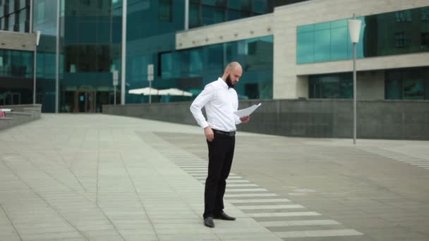 Businessman throwing paper near office building — Stock Video