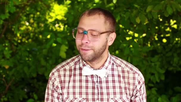 Молодий чоловік в окулярах дивиться в камеру, фіксуючи свою краватку — стокове відео