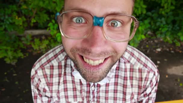 Jonge man in glazen staren naar de camera en lachen hyster — Stockvideo