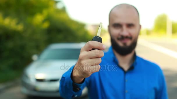 Smiling man with beard near the car showing key — Stock Video