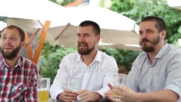 Мужчины с бородами сидят в кафе, пьют пиво — стоковое видео