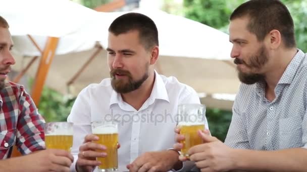 Tres hombres en la cafetería bebiendo cerveza ligera, hablando — Vídeo de stock