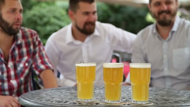 Drei Männer sitzen im Café im Freien und schauen sich Match an — Stockvideo