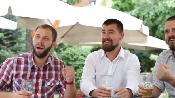 Trois hommes assis dans un café, buvant de la bière et faisant des photos par la foule — Video