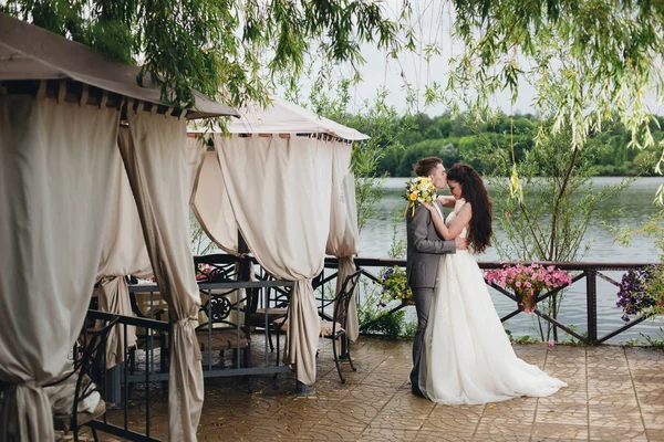Brudgummen kyssa bruden på verandan — Stockfoto