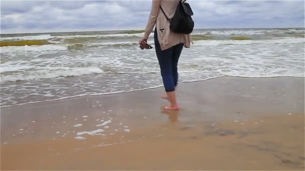 En tjej går längs stranden, gå barfota längs kusten — Stockvideo