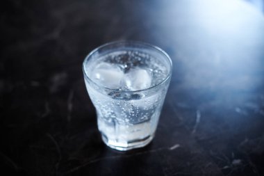 Siyah mermer bir yüzey üzerinde buzla servis edilen cin tonik kokteyli.