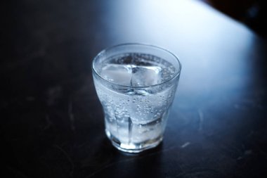 Siyah mermer bir yüzey üzerinde buzla servis edilen cin tonik kokteyli.