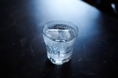 Siyah mermer bir yüzey üzerinde buzla servis edilen cin tonik kokteyli.