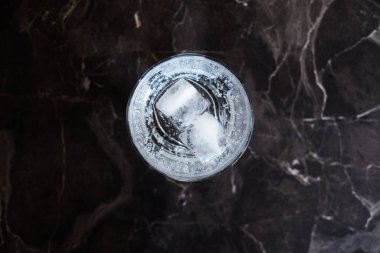 Siyah mermer bir yüzey üzerinde buzla servis edilen cin tonik kokteyli.