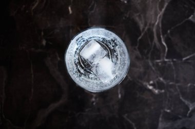 Siyah mermer bir yüzey üzerinde buzla servis edilen cin tonik kokteyli.