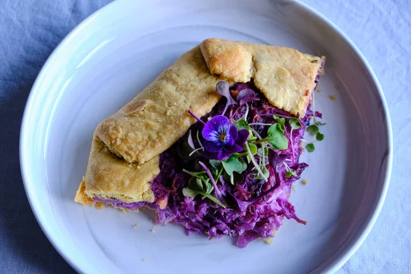 Red Cabbage and Goat Cheese Galette with edible flowers and micro green