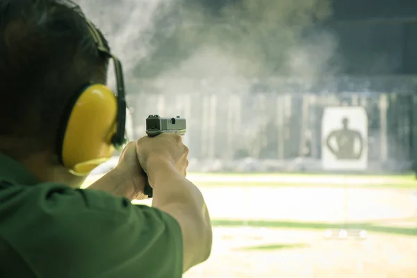 Człowiek strzelanie pistoletu automatycznego do obiektu docelowego w strzelnicy — Zdjęcie stockowe