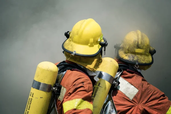 Dos bomberos fuego lucha contra el humo oscuro — Foto de Stock