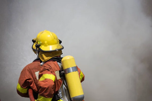 Due vigili del fuoco che combattono intorno al fuoco con fumo scuro — Foto Stock