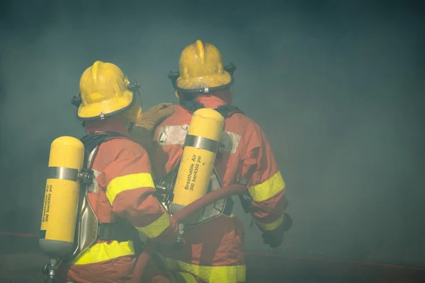 Two firefighters fire fighting suround with dark smoke — Stock Photo, Image