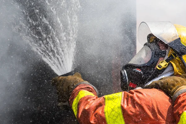 Firefighter water spray by high pressure fire hose — Stock Photo, Image