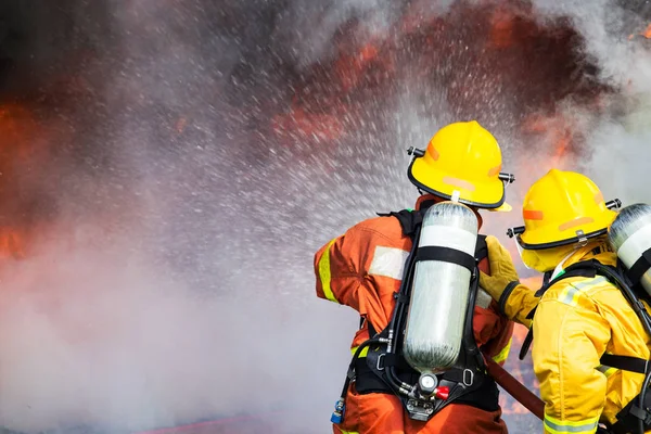 Two firefighters water spray by high pressure nozzle to fire sur — Stock Photo, Image