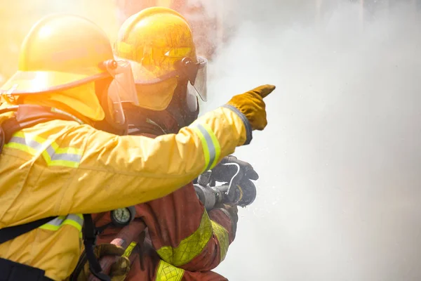 Twee brandweerlieden water spray door hoge druk sproeier te vuren sur — Stockfoto
